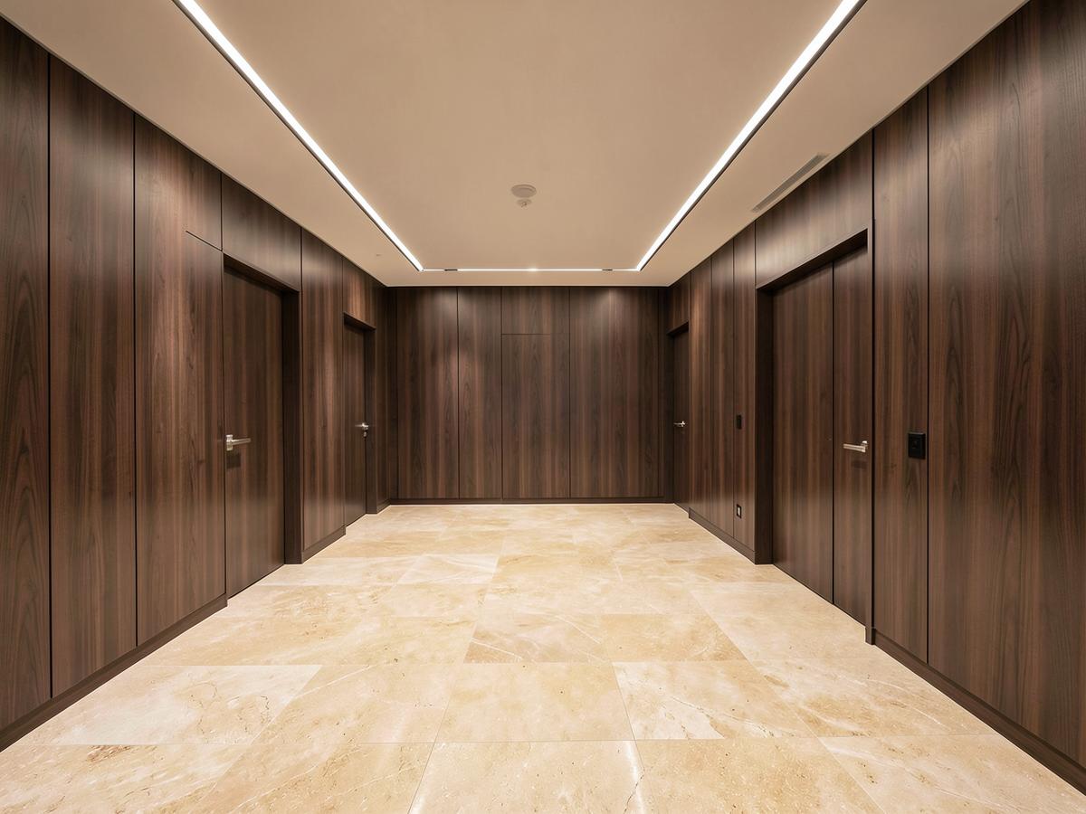 The same condominium lobby after refurbishment with stone flooring, walnut panelling and modern linear lighting